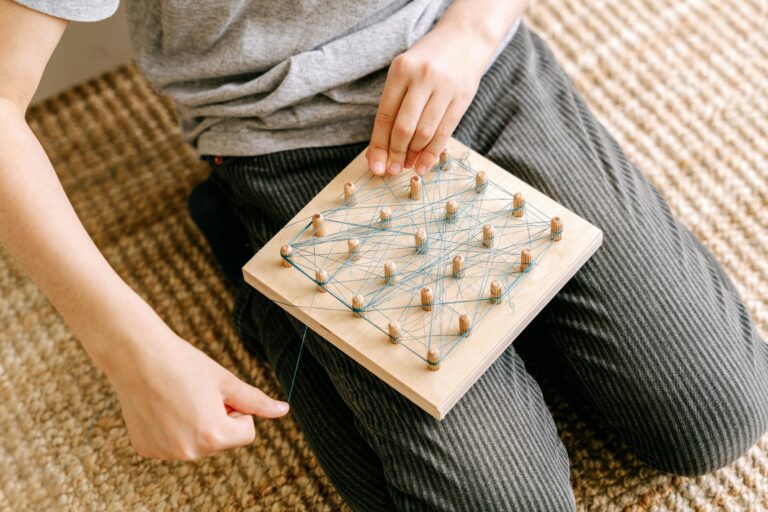 Little boy playing with string on a wooden board