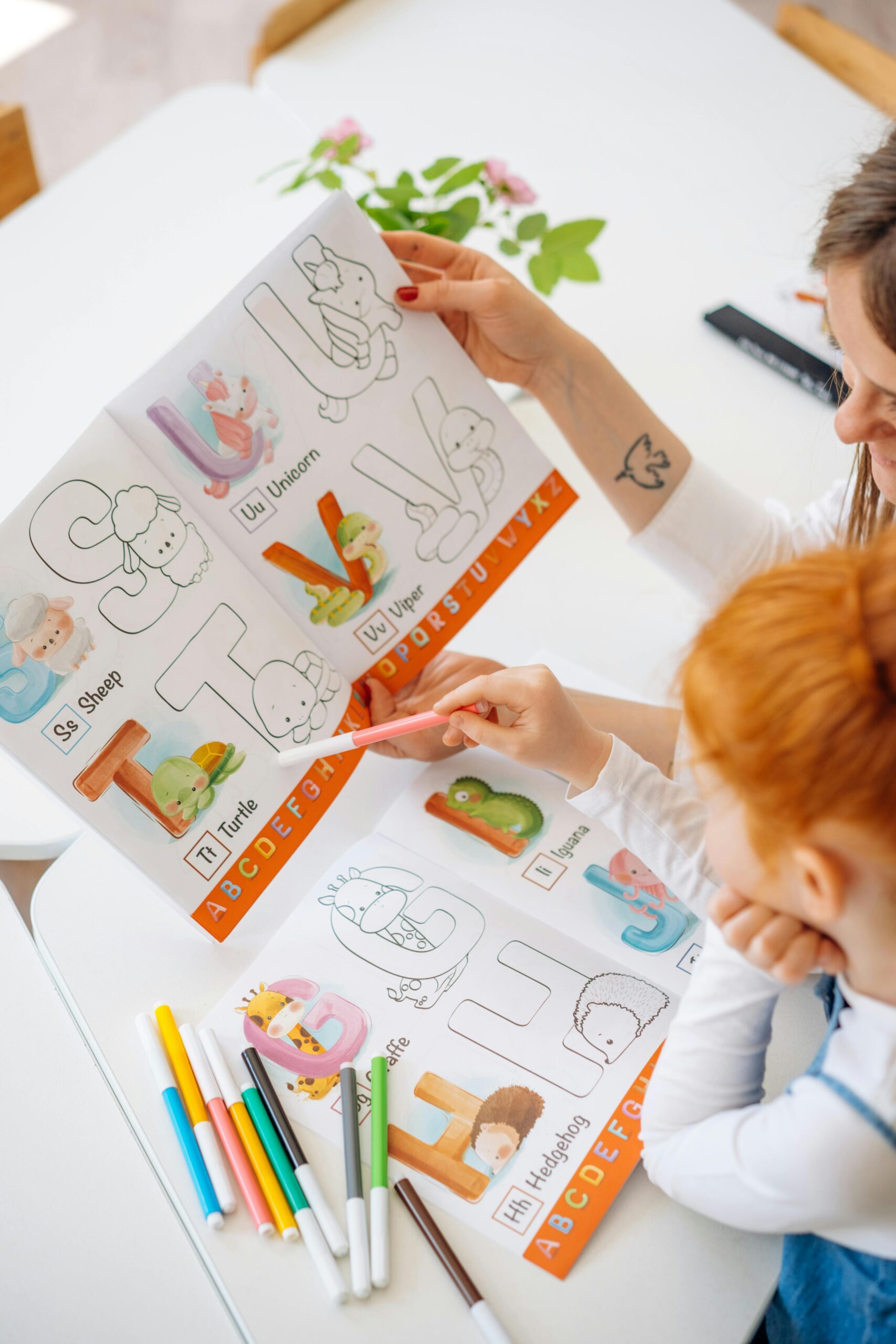 A mom with a little girl working on coloring ABC worksheets together