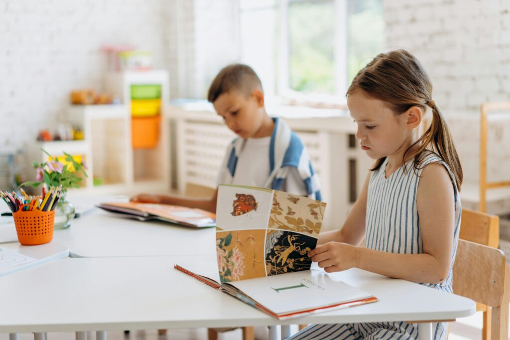 A little girl and a little boy doing school at a table in an educational room