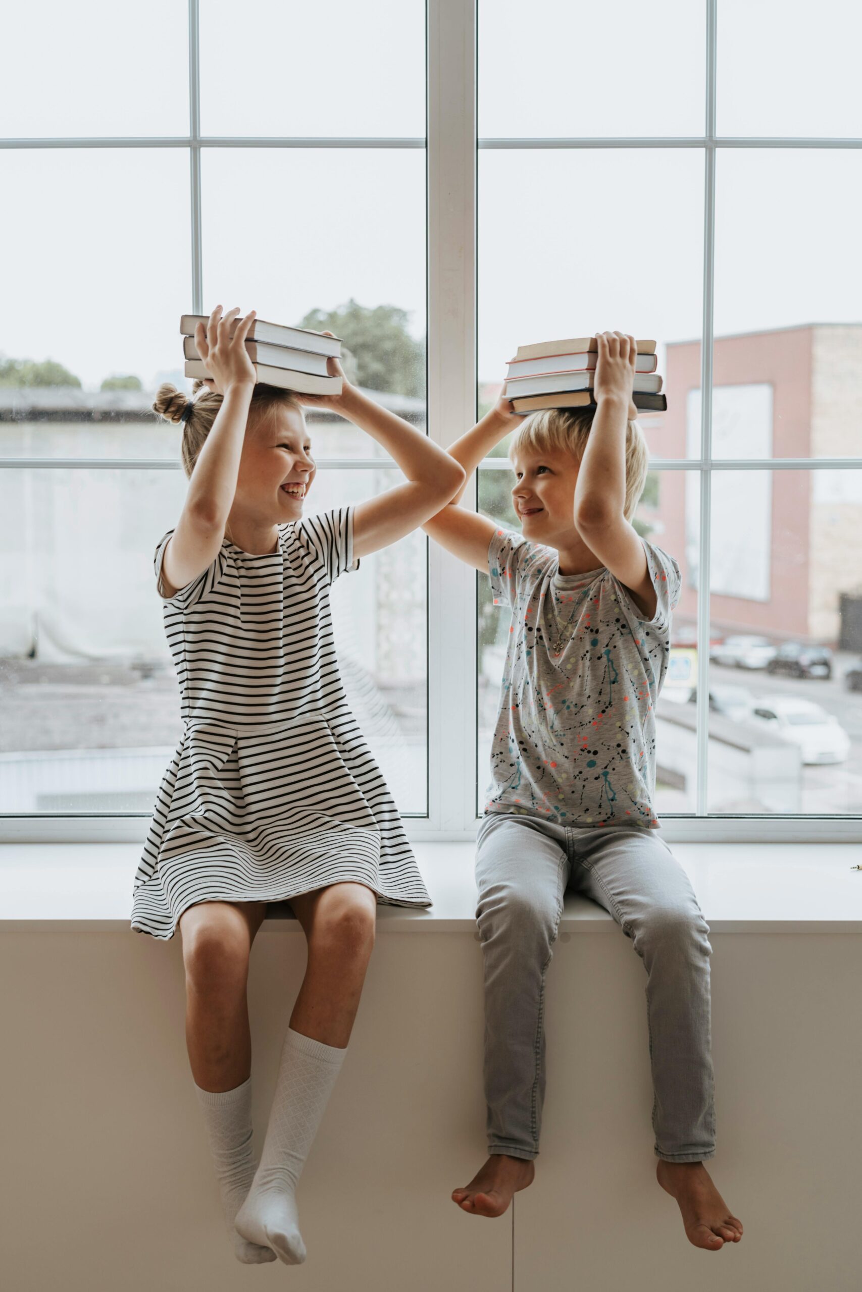 A little boy and a little girl sitting together holding stacks of books